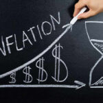 Chalkboard drawing of inflation with rising dollar symbols.