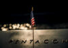 American flag above engraved Pentagon sign at night