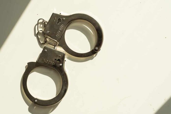 A pair of metallic handcuffs resting on a light surface