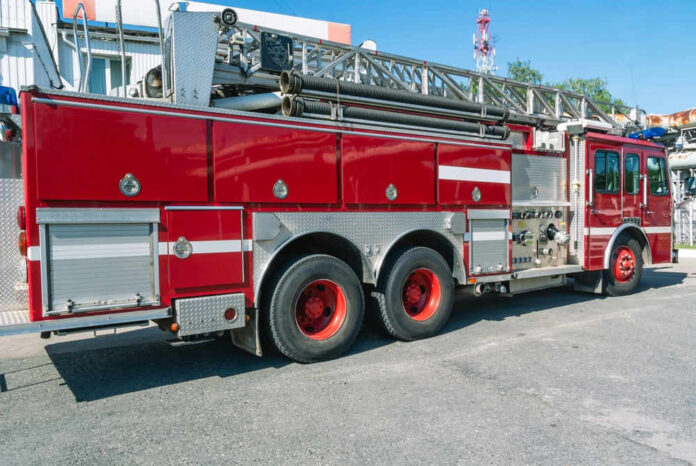 shutterstock_2357242883.jpg Red fire truck with ladder parked outside building