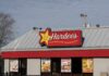 Exterior view of a Hardee's restaurant with signage and promotional posters