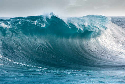 A large ocean wave curling with vibrant blue hues