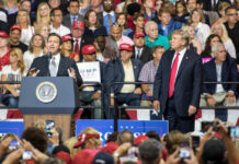 DeSantis Renames Airport TRUMP A man speaks at a podium as another man watches.
