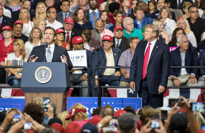 A man speaks at a podium as another man watches.