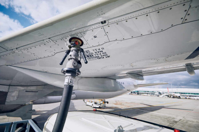 shutterstock_1344570161.jpg Fueling equipment attached to an airplane wing at an airport