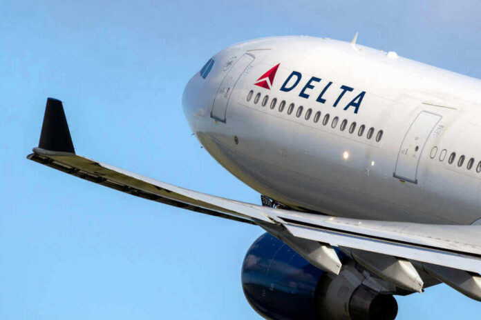 Delta airplane in flight with blue sky background.