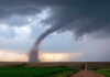Tornado touching down in an open field area.