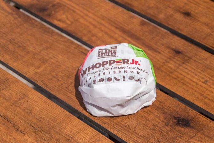 A wrapped Whopper Jr. burger resting on a wooden table