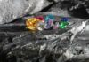 A variety of colorful gemstones resting on a dark stone surface
