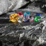 A variety of colorful gemstones resting on a dark stone surface