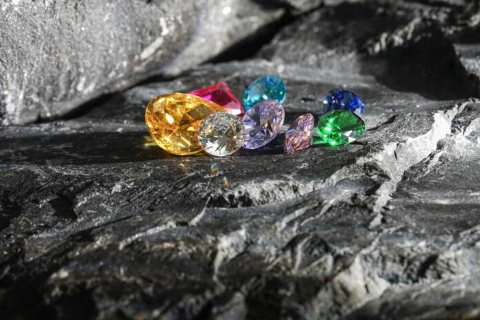 A variety of colorful gemstones resting on a dark stone surface