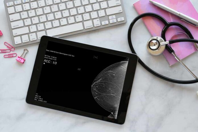 A tablet displaying a mammogram image on a desk with medical tools