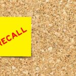 Yellow sticky note with the word 'RECALL' on a corkboard
