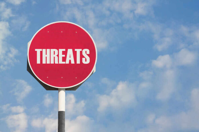 shutterstock_241274614.jpg Red sign with the word threats against sky