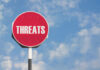 Red sign with the word threats against sky