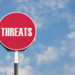 Cartel Threats Force AG Onto Base Red sign with the word threats against sky