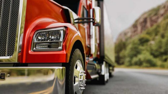 Close-up of a red truck on a road with a mountainous background