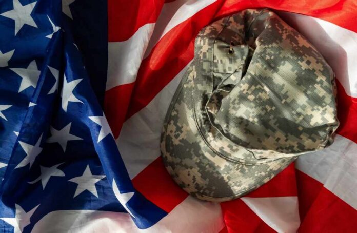 Camouflage military cap resting on an American flag