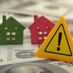 Mortgage Demand CRASHES As Rates Spike Colorful house models and a warning sign on dollar bills