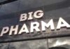 Sign displaying the words BIG PHARMA on a glass building