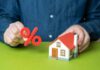 Person holding a percentage symbol above a model house