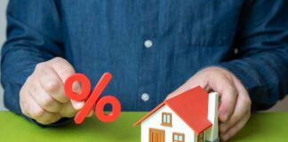 Person holding a percentage symbol above a model house