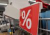 Red discount sign with a percentage symbol in a retail setting