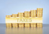 Stacked coins with TAXES on block beneath.