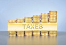 Stacked coins with TAXES on block beneath.