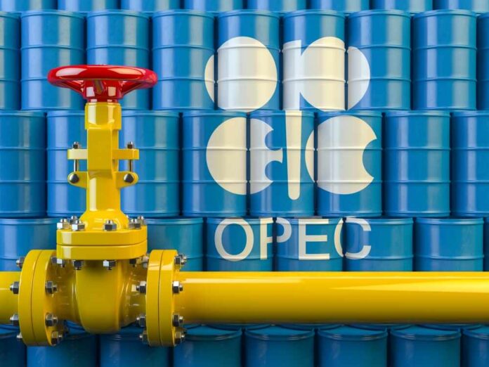 Yellow pipeline valve in front of blue oil barrels with OPEC logo