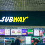 Subway restaurant sign with menu displays in the background