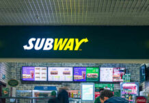 Subway restaurant sign with menu displays in the background