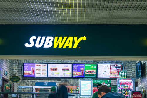 Subway restaurant sign with menu displays in the background