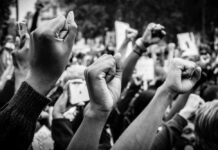 Raised fists at a protest rally, black and white image.