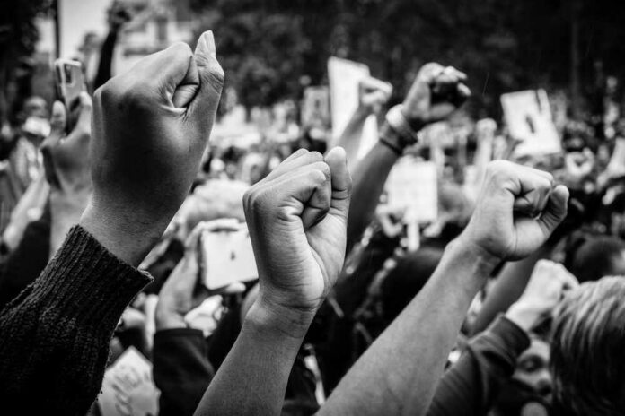 Raised fists at a protest rally, black and white image.