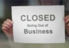 A person holding a sign that reads 'CLOSED Going Out of Business'