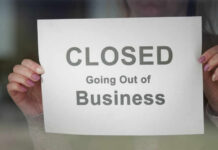A person holding a sign that reads 'CLOSED Going Out of Business'