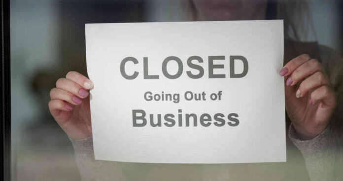 A person holding a sign that reads 'CLOSED Going Out of Business'