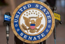 United States Senate seal with microphones in front.