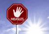 Stop sign with a hand symbol and the word 'MEASLES'