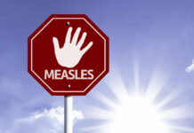 Stop sign with a hand symbol and the word 'MEASLES'