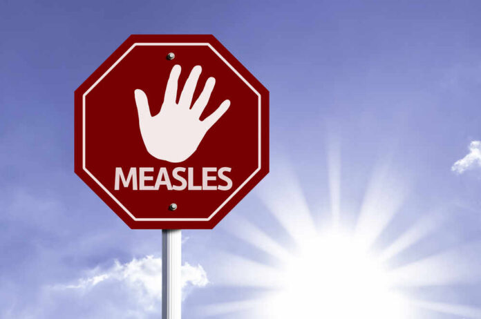 Stop sign with a hand symbol and the word 'MEASLES'