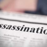 Close-up of a newspaper headline reading 'Assassination'