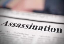 Close-up of a newspaper headline reading 'Assassination'