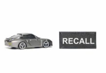 A miniature gray sports car next to a black sign that reads 'RECALL'