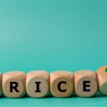 Wooden blocks spelling 'PRICE' with arrows indicating increase and decrease