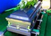 A silver casket adorned with flowers at a gravesite