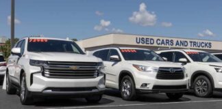 Two white SUVs parked at a used car dealership with price tags visible