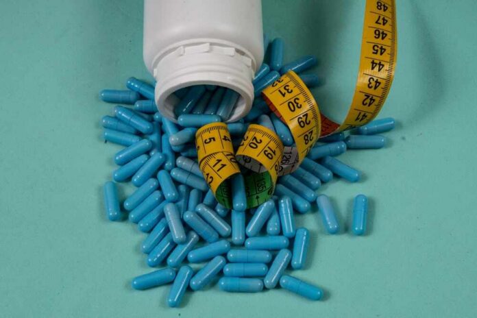 Spilled blue capsules and a measuring tape on a turquoise background
