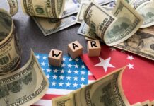 Iran War Forces IMF Forecast Reversal Bombshell Dollar bills surrounding wooden blocks spelling 'WAR' on flags of the USA and China